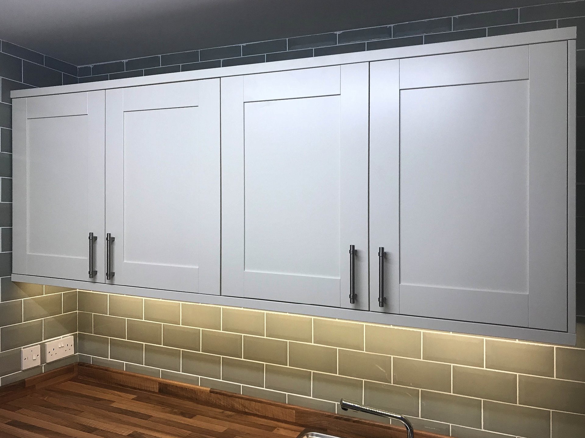 Bank of wall hung cabinet units with under pelmet led lighting part of kitchen installation. Barnstaple Devon
